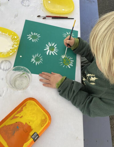 child painting flowers on green paper