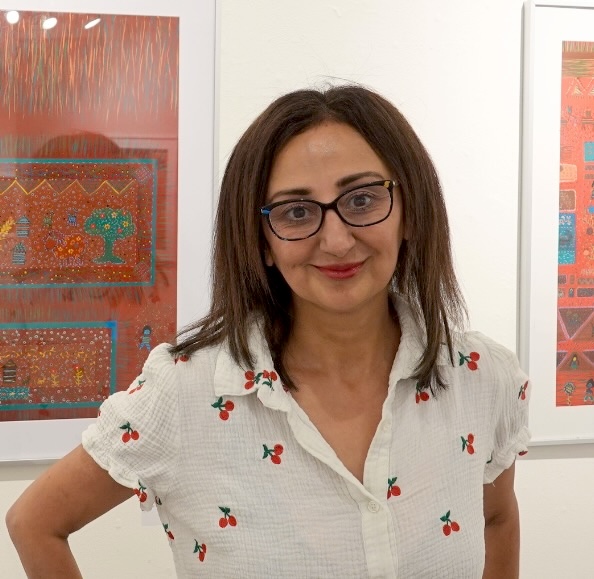 Fedra Yazdi portrait, standing before framed artwork