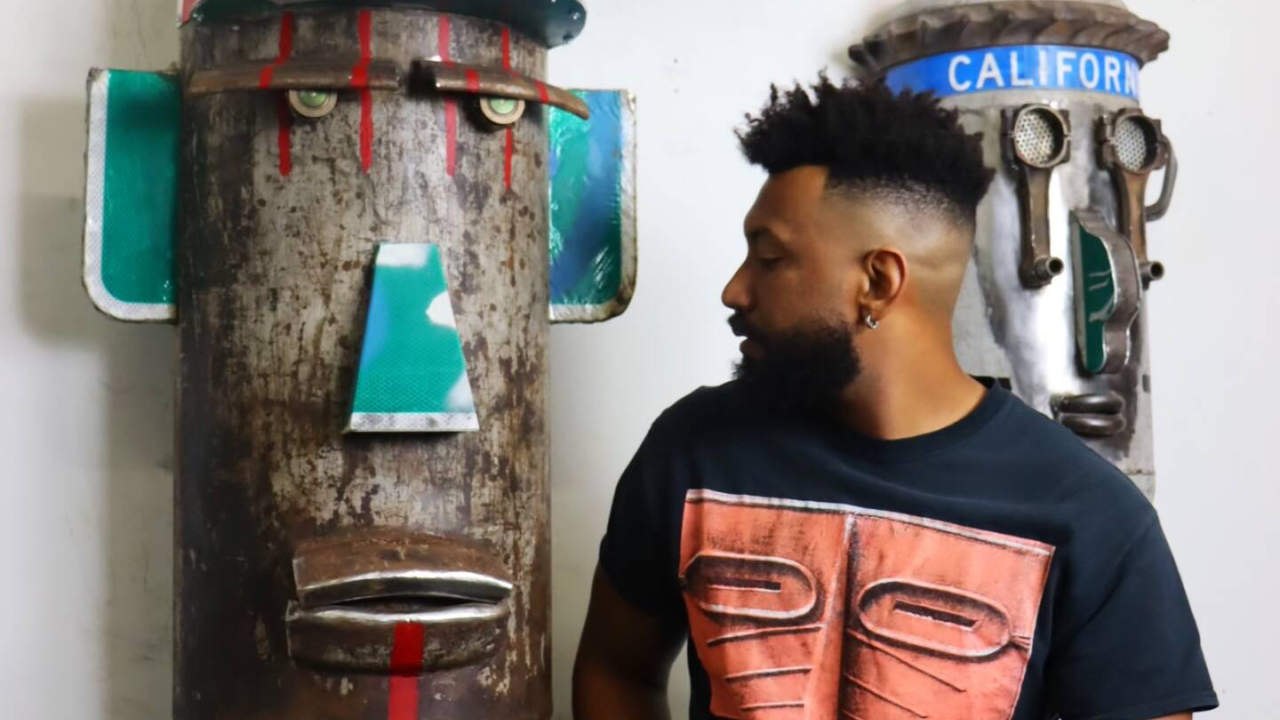 Artist Zulu Hero in profile next to his found media sculptures