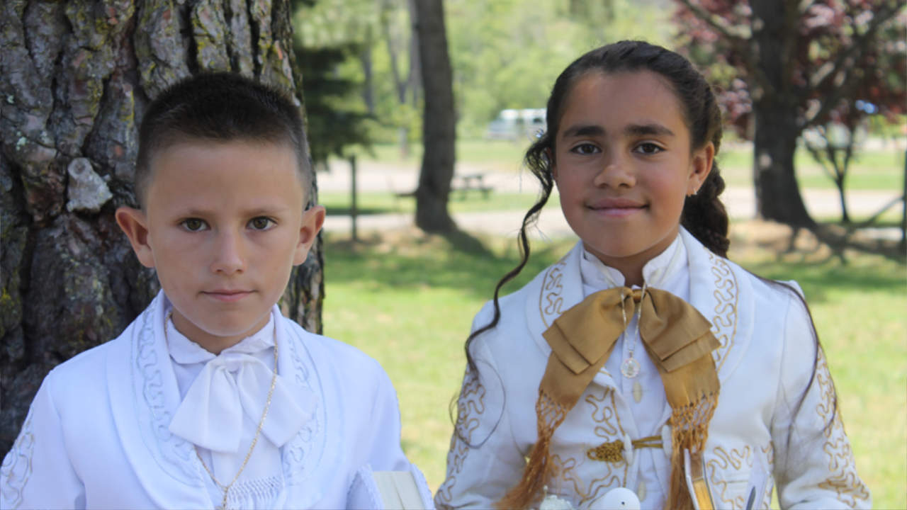 Two young Hispanic children looking into camera in closeup under a tree